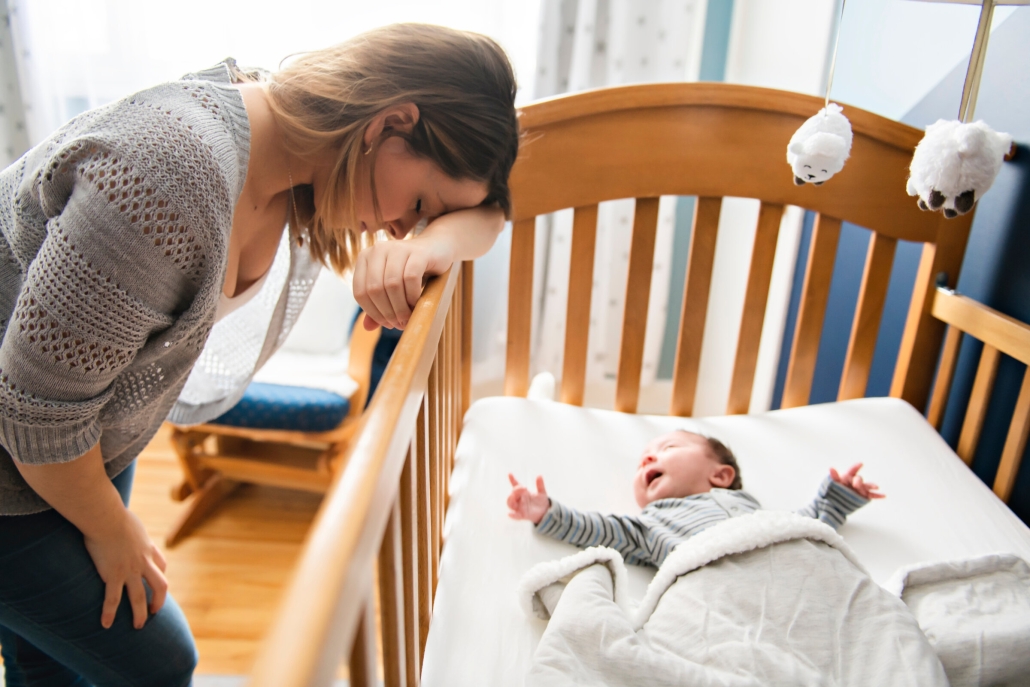 Mom overwhelmed next to crib